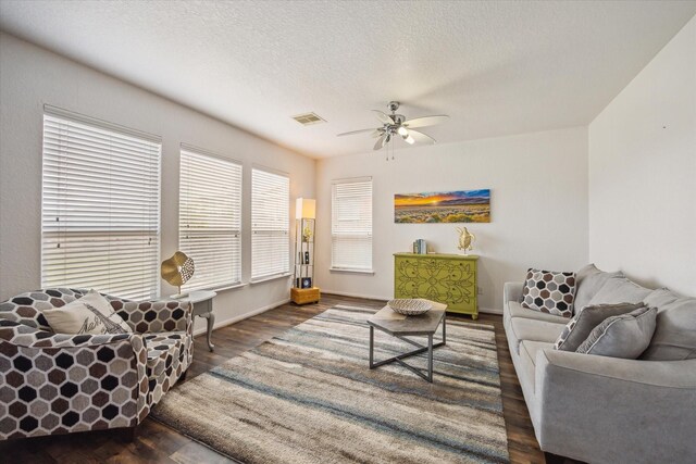 living area with ceiling fan, a textured ceiling, baseboards, wood finished floors, and visible vents