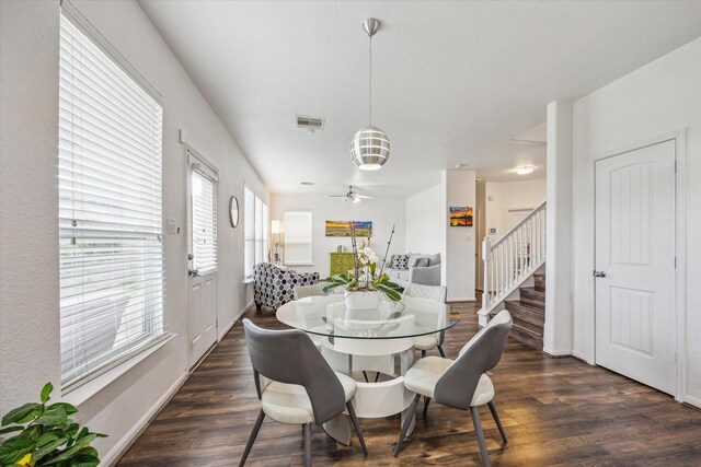 dining space featuring a wealth of natural light, dark wood-style flooring, stairs, and visible vents