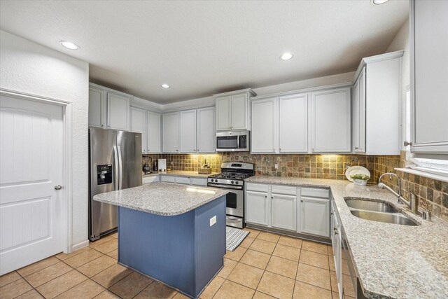 kitchen with a kitchen island, appliances with stainless steel finishes, a sink, and tasteful backsplash