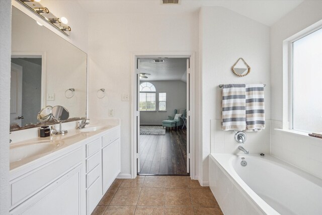 full bathroom featuring a sink, tile patterned floors, a garden tub, and double vanity