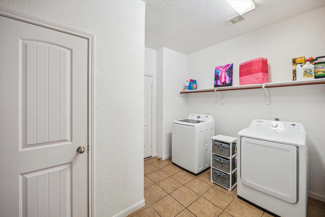 laundry area with laundry area, visible vents, a textured ceiling, separate washer and dryer, and light tile patterned floors