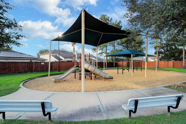 community play area with a lawn and fence