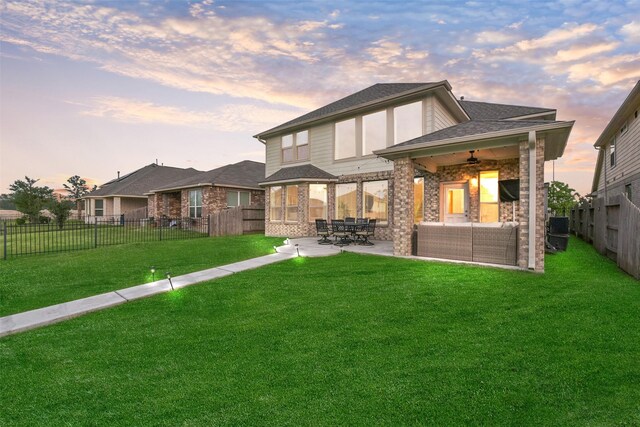 back of property featuring an outdoor living space, a patio area, brick siding, a fenced backyard, and a yard