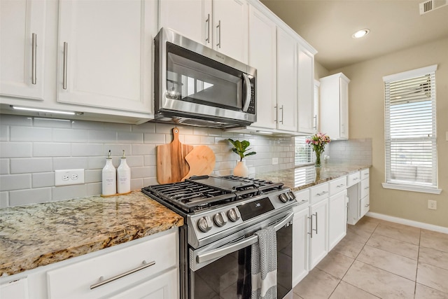 kitchen with visible vents, baseboards, light stone counters, stainless steel appliances, and white cabinetry