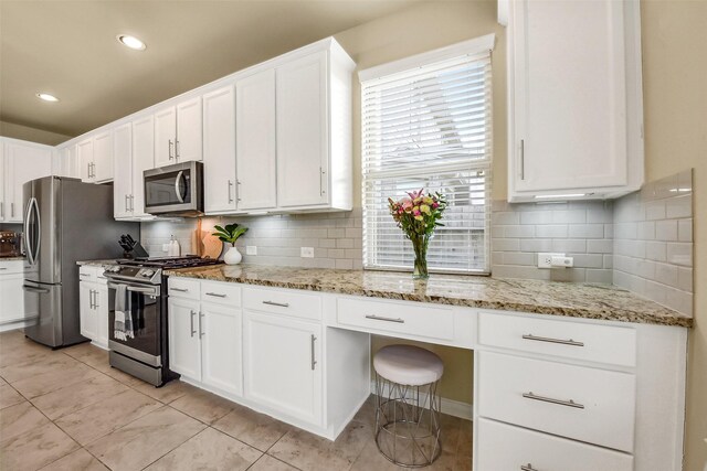kitchen with backsplash, light stone counters, light tile patterned flooring, stainless steel appliances, and white cabinetry