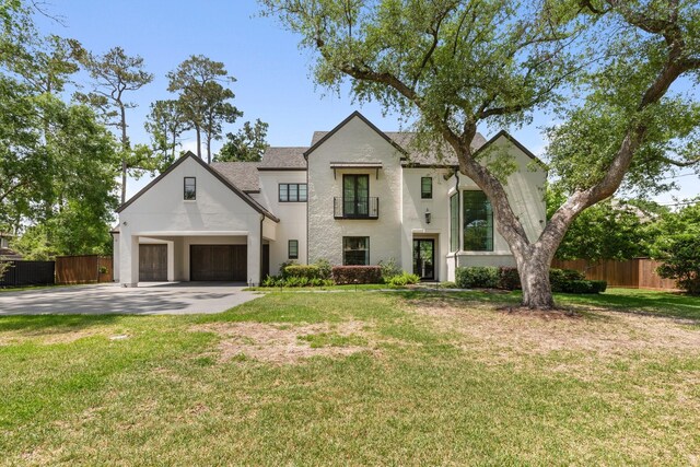 view of front of property featuring concrete driveway, fence, a front lawn, and stucco siding