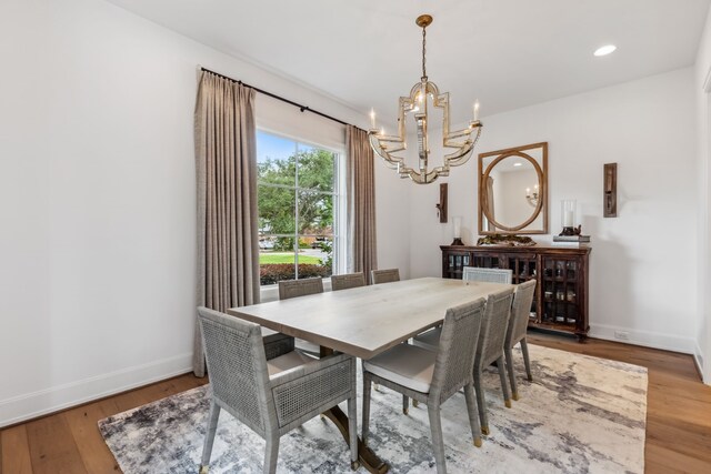 dining space with baseboards, recessed lighting, wood finished floors, and a notable chandelier