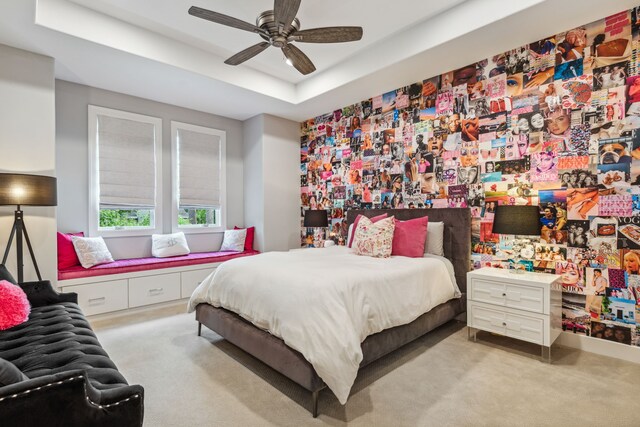 bedroom featuring a raised ceiling, carpet, and a ceiling fan