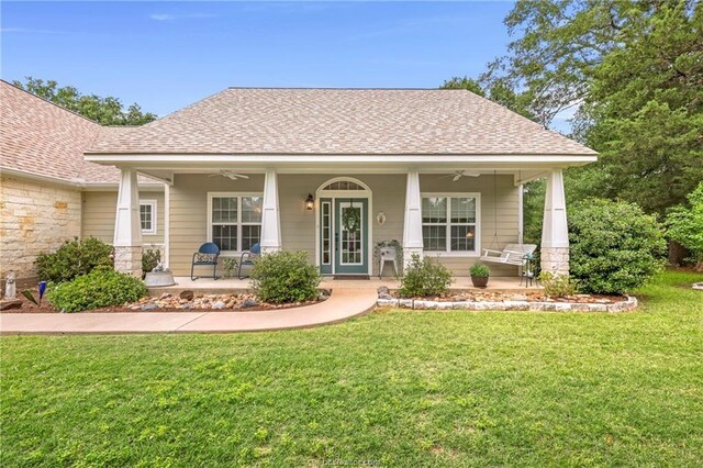 view of front of house with a porch, a shingled roof, ceiling fan, and a front lawn