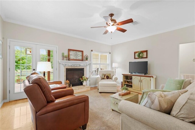 living area featuring french doors, a ceiling fan, visible vents, a fireplace, and ornamental molding