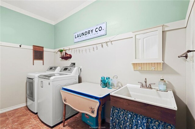 washroom featuring laundry area, crown molding, baseboards, washing machine and clothes dryer, and a sink