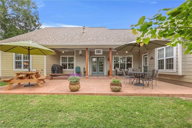 rear view of house featuring french doors, a lawn, a patio area, and roof with shingles