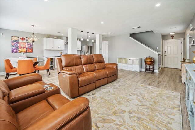 living area featuring an inviting chandelier, light wood finished floors, recessed lighting, baseboards, and visible vents