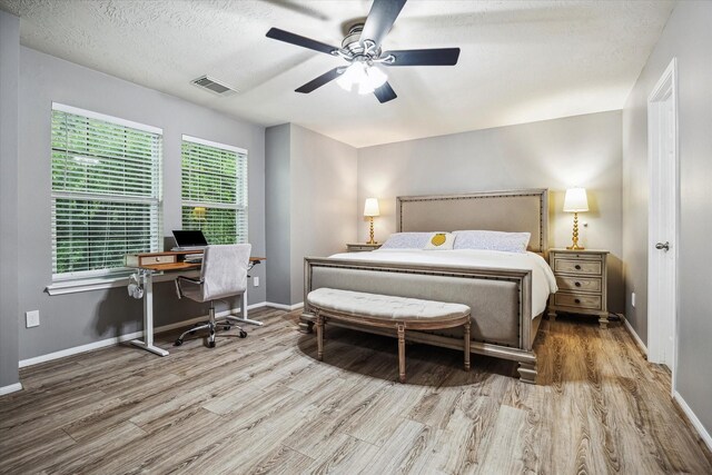bedroom featuring ceiling fan, a textured ceiling, visible vents, wood finished floors, and baseboards