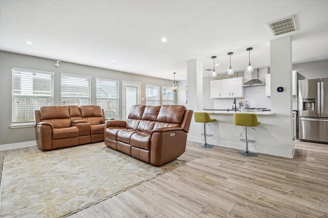 living area with recessed lighting, baseboards, visible vents, and light wood-type flooring