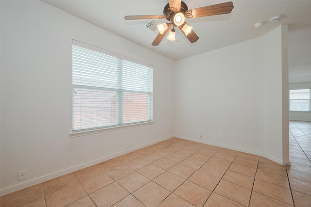 unfurnished room featuring a ceiling fan, baseboards, and light tile patterned floors