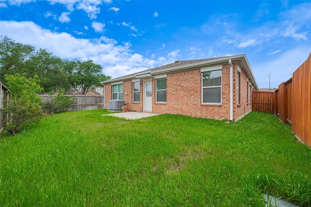 back of property with a yard, brick siding, and a fenced backyard