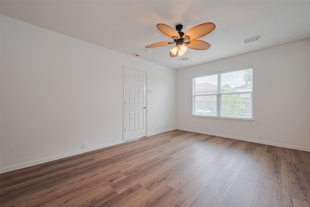 spare room with baseboards, ceiling fan, wood finished floors, and visible vents