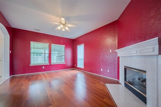 526 Majestic Ridge Dr, Houston, TX 77049 - unfurnished living room featuring arched walkways, a ceiling fan, a tile fireplace, visible vents, and hardwood / wood-style flooring