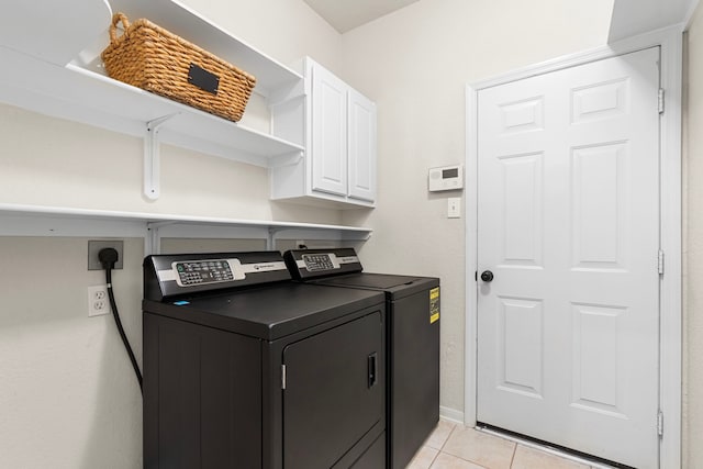 washroom with light tile patterned floors, baseboards, washing machine and dryer, and cabinet space
