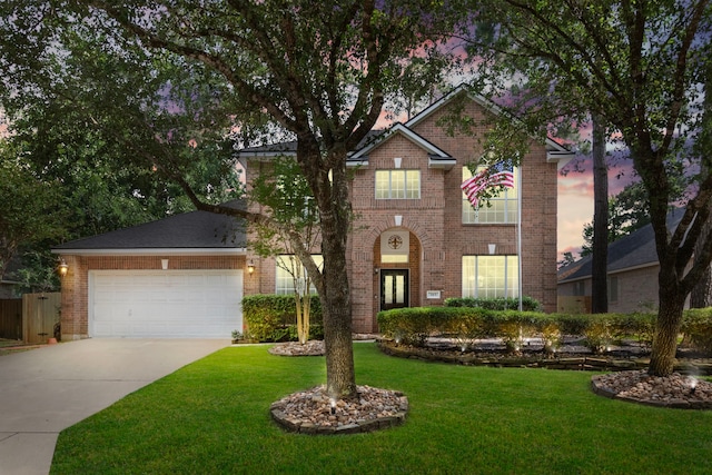 traditional-style home with brick siding, an attached garage, driveway, and a front yard