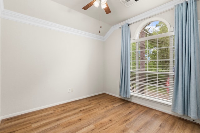 empty room featuring crown molding, ceiling fan, light wood-style flooring, lofted ceiling, and visible vents