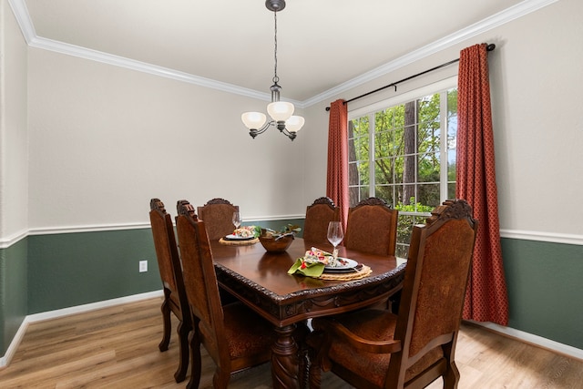 dining space with crown molding, baseboards, wood finished floors, and a notable chandelier