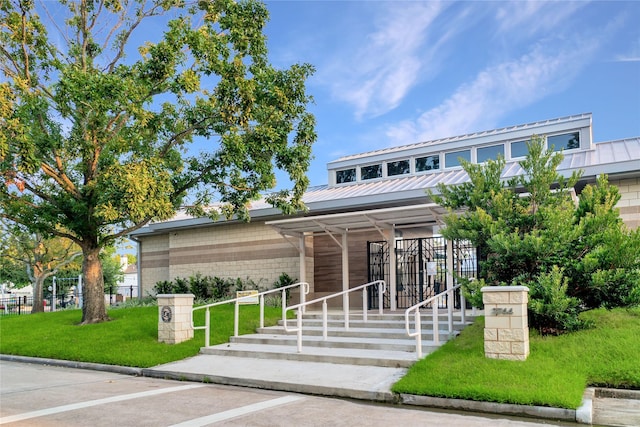 exterior space featuring a standing seam roof, covered porch, metal roof, and a front lawn