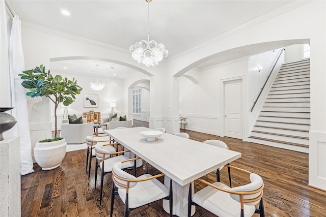 dining area with arched walkways, a wainscoted wall, wood finished floors, ornamental molding, and stairway