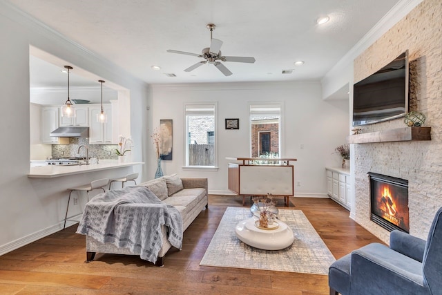 1267 Sopris Dr, Houston, TX 77077 - living room featuring a fireplace, a ceiling fan, crown molding, hardwood / wood-style floors, and baseboards