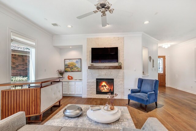 1267 Sopris Dr, Houston, TX 77077 - living area featuring wood finished floors, a stone fireplace, ornamental molding, a ceiling fan, and baseboards