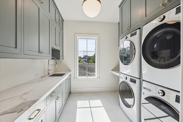 laundry area with stacked washing machine and dryer, cabinet space, light tile patterned floors, and washing machine and dryer