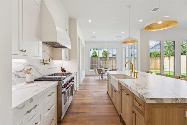 kitchen featuring range with two ovens, a sink, premium range hood, light wood-style floors, and recessed lighting