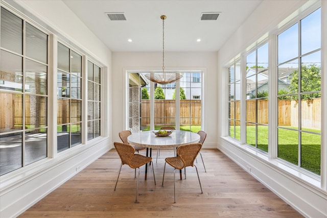 sunroom / solarium with a chandelier, wood finished floors, baseboards, recessed lighting, and a wooden deck