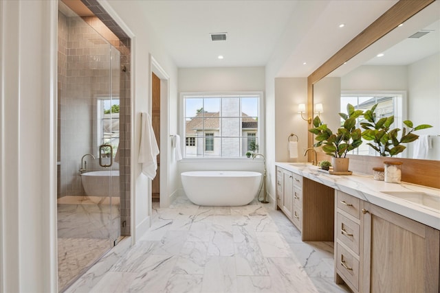 full bathroom with double vanity, plenty of natural light, a stall shower, a freestanding tub, and recessed lighting