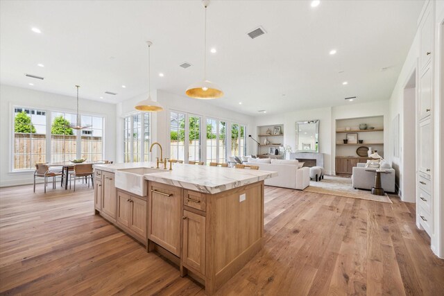4230 Whitman St, Houston, TX 77027 - kitchen with a sink, light wood finished floors, a center island with sink, hanging light fixtures, and recessed lighting