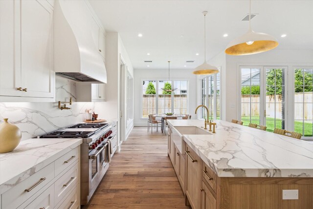 4230 Whitman St, Houston, TX 77027 - kitchen featuring double oven range, a sink, custom range hood, light wood-style flooring, and decorative backsplash