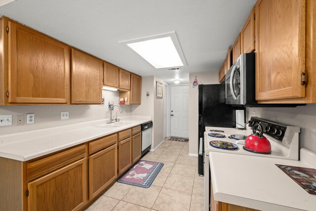 kitchen featuring brown cabinetry, white appliances, light countertops, a sink, and light tile patterned floors