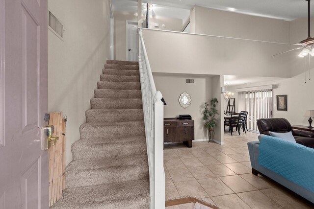 staircase with tile patterned flooring, ceiling fan with notable chandelier, and visible vents