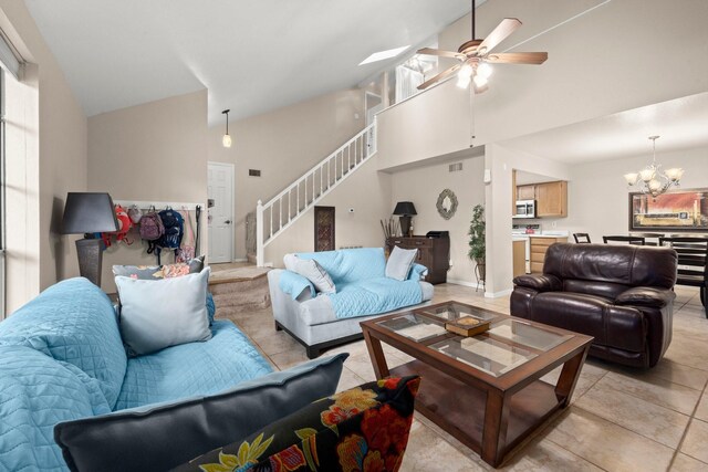 living room with visible vents, high vaulted ceiling, stairway, ceiling fan with notable chandelier, and light tile patterned floors