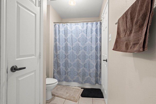 full bathroom featuring shower / bathtub combination with curtain, tile patterned floors, and toilet