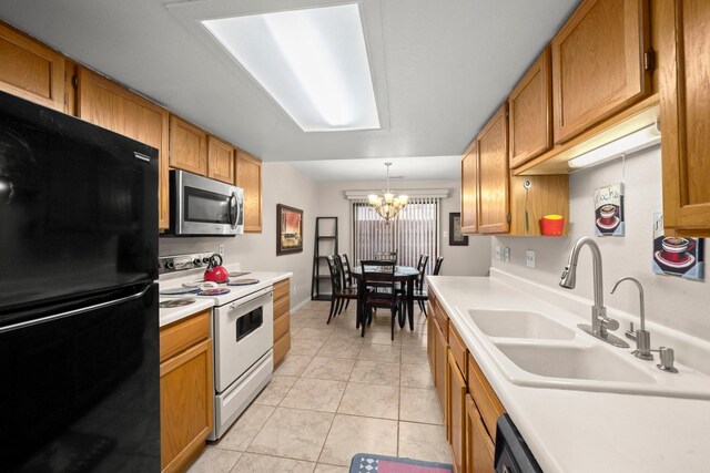 kitchen with white range with electric stovetop, a notable chandelier, a sink, freestanding refrigerator, and stainless steel microwave