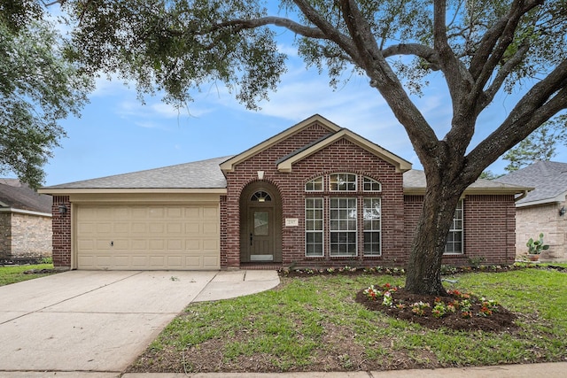 ranch-style home featuring roof with shingles, an attached garage, brick siding, a front yard, and driveway