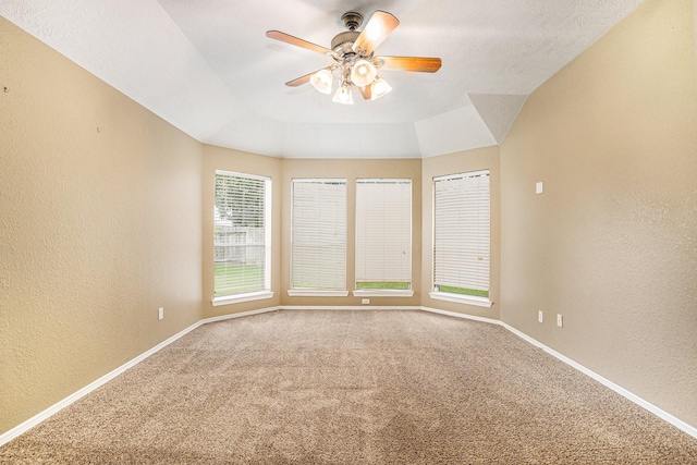 carpeted empty room featuring baseboards, a textured wall, and a ceiling fan