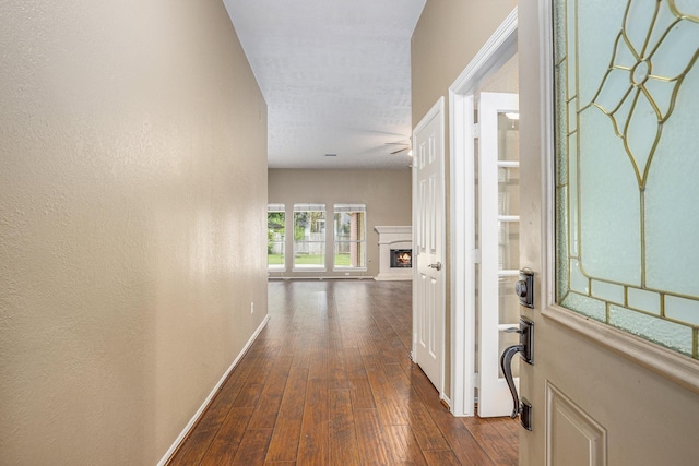hall featuring dark wood-type flooring and baseboards