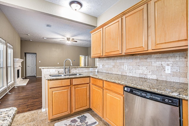 kitchen featuring a sink, decorative backsplash, stainless steel dishwasher, and a peninsula