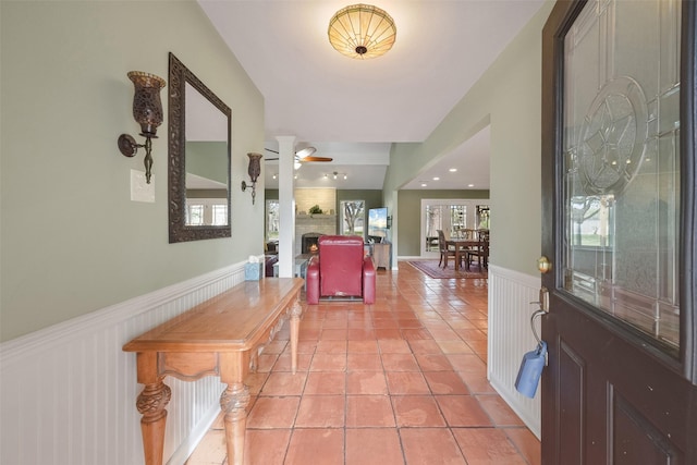 2711 N Saddlebrook Ln, Katy, TX 77494 - entryway with light tile patterned floors, a wainscoted wall, a brick fireplace, and a wealth of natural light
