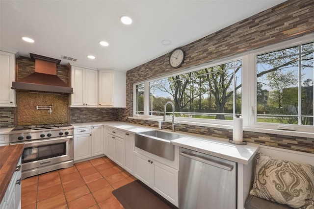 2711 N Saddlebrook Ln, Katy, TX 77494 - kitchen featuring appliances with stainless steel finishes, a sink, premium range hood, light tile patterned floors, and visible vents