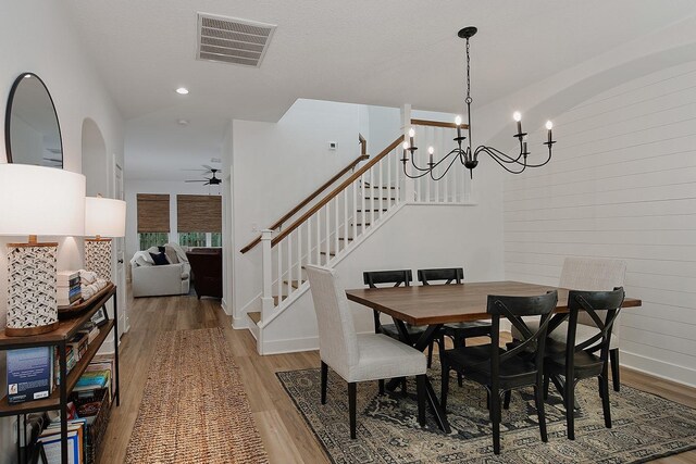 dining space featuring stairway, visible vents, ceiling fan with notable chandelier, and light wood-type flooring