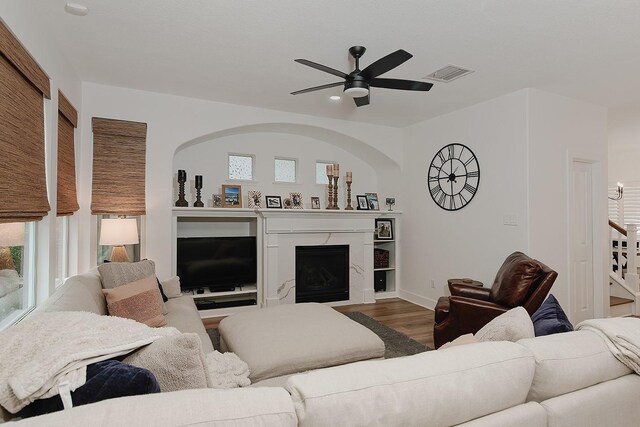 living room featuring a healthy amount of sunlight, a ceiling fan, visible vents, a fireplace, and wood finished floors
